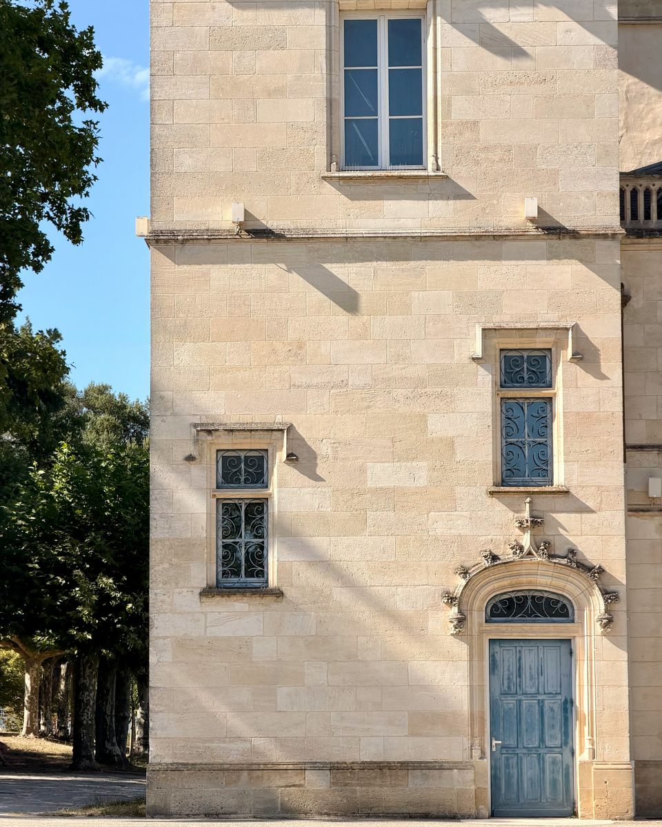 Façade en pierre de taille claire, fenêtres à meneaux et porte bleu nuit