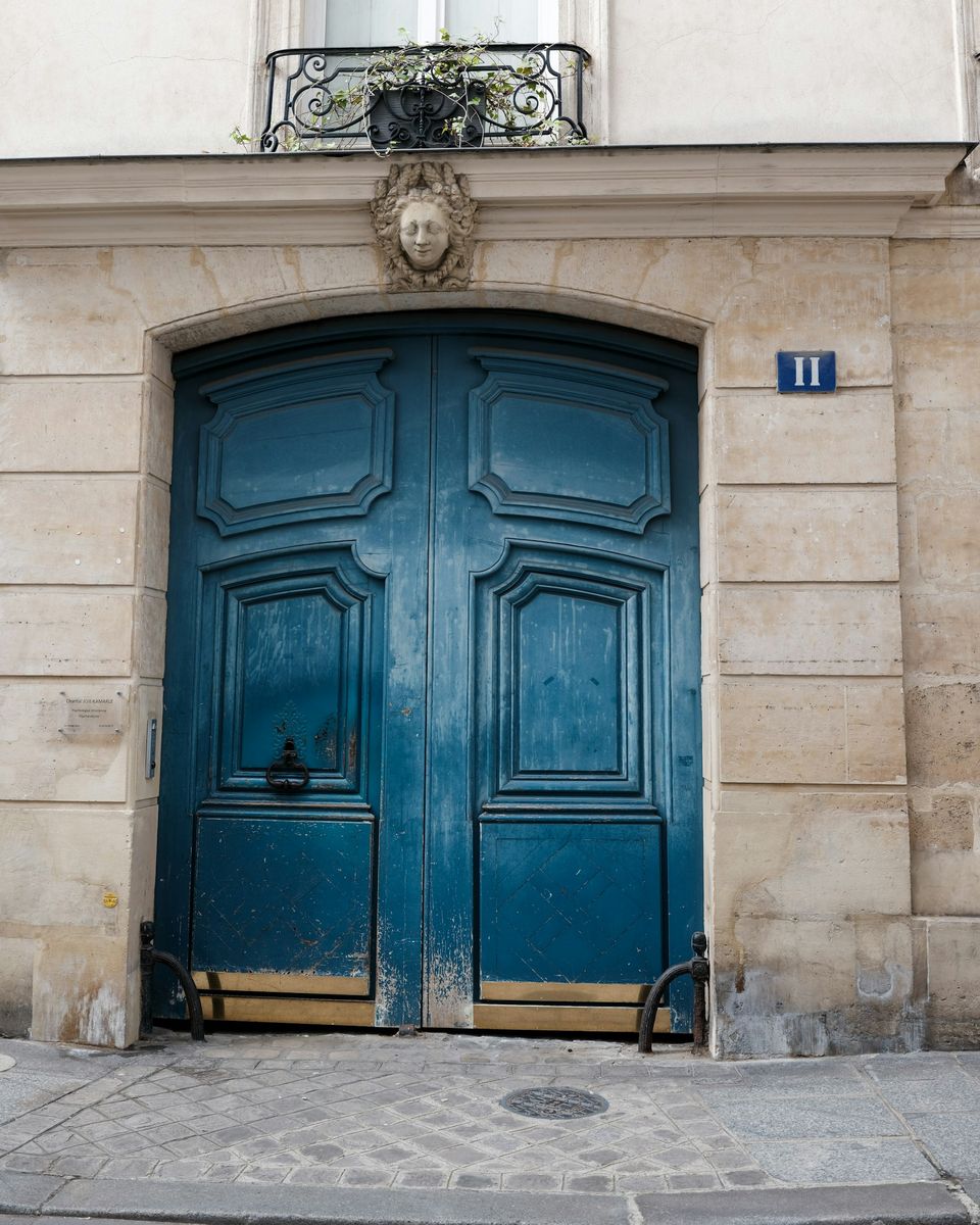 Porte cochère bleu nuit dans une façade de pierre claire